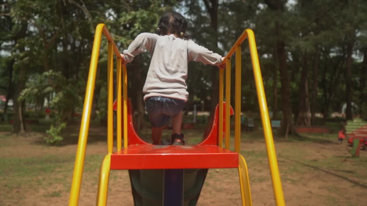 Bambino che fa lo scivolo al parco giochi