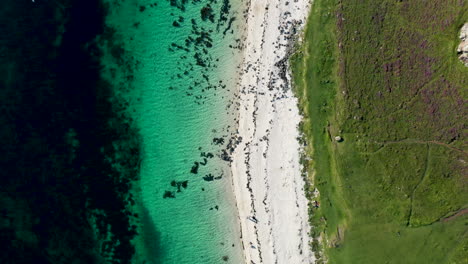 downward angle drone shot of coral beach in claigan with white sandy beaches and tropical blue water, in scotland