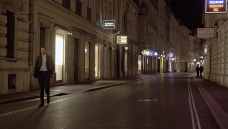 Man Walking Down a Lit City Street at Night