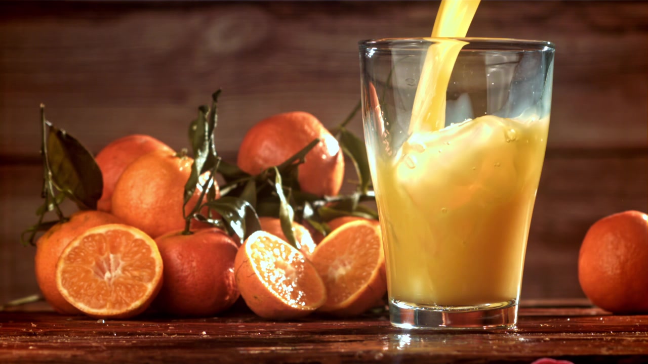 Fresh Orange Juice Poured into a Glass with Tangerines on a Wooden Table