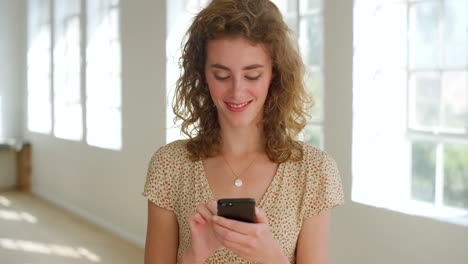 happy young woman texting on a phone at home