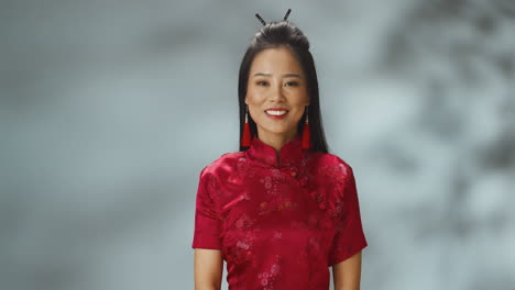 Retrato-De-Una-Joven-Asiática-Alegre-Vestida-Con-Ropa-Tradicional-Roja-Sonriendo-A-La-Cámara
