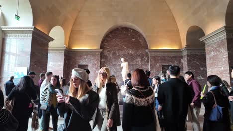 people looking at venus de milo at the louvre museum paris. public admiring ancient greek marble sculpture