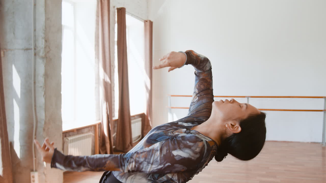 Woman gracefully dancing in a sunlit studio