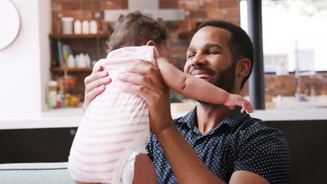 father lifting baby daughter into the air and smiling at home