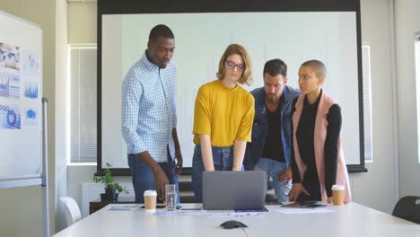 front view of mixed race business team discussing over laptop in modern office 4k