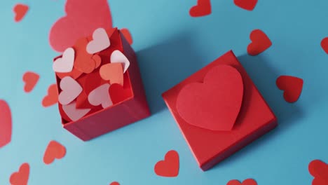 cajas rojas con corazones de papel sobre un fondo azul en el día de san valentín