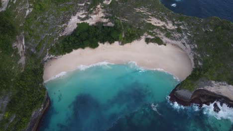 kelingking beach on nusa penida island and white sand cove down a lush steep rock face cliff