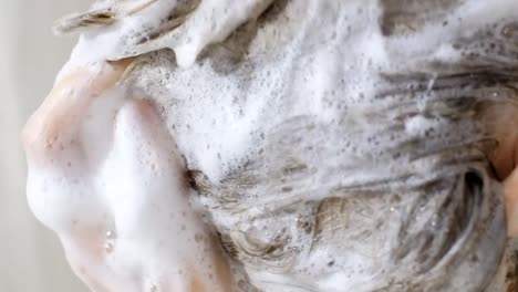 a girl who instantly washes her long hair with shampoo while standing under the shower in the bathroom.