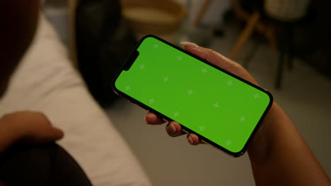 mujer sosteniendo un teléfono inteligente con una pantalla verde