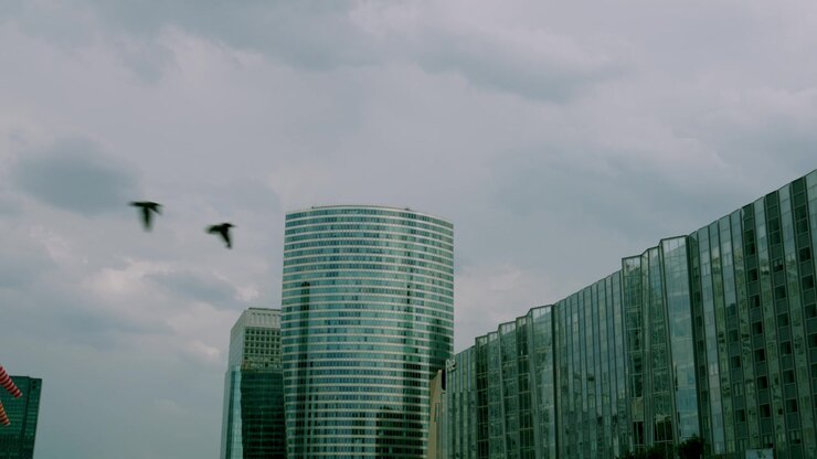 Torre di vetro rotonda contro un cielo nuvoloso, ripresa ampia, torre rotonda, edificio in vetro, architettura, La Défense, aziendale, Parigi, Francia, urbano, video HD, filmato stock, b-roll, esterno, all'aperto, diurno