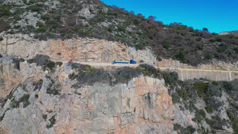 un camión conduciendo a lo largo de una pintoresca carretera costera en el acantilado de port ginesta barcelona, vista aérea