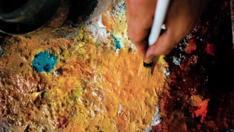 macro of artist applying yellow color to the painting