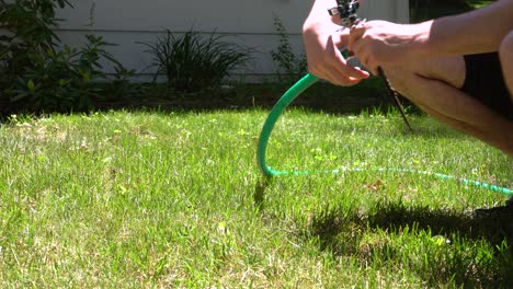 a man unhooks an old school mechanical sprinkler in the heat of summer