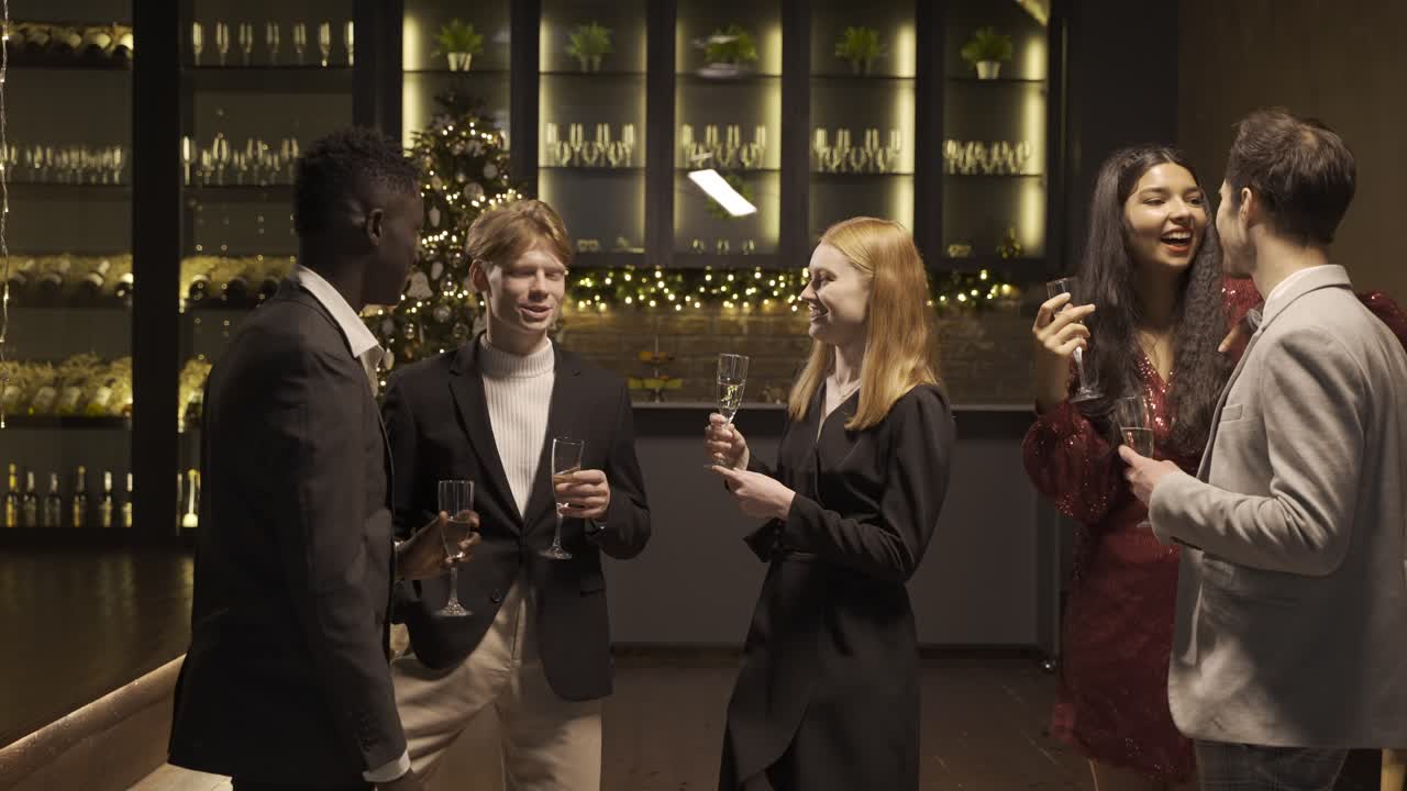 Group of friends wearing elegant clothes talking while they holding champagne glasses in new year's party