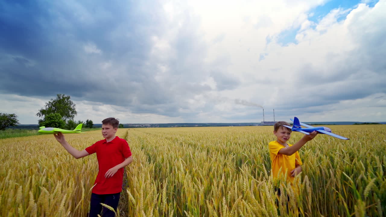 Boys with toys outdoors. Children play on a wheat field. Brothers launch plastic toy planes among nature. Happy childhood in summer.