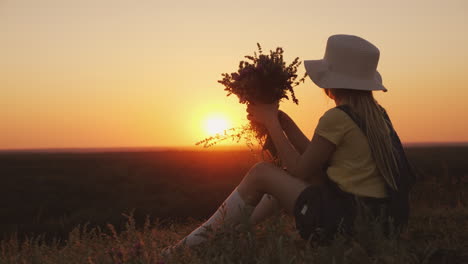 A-Girl-In-A-Hat-Admires-The-Sunset-In-A-Picturesque-Place-She-Sits-On-A-Hill-Her-Chin-On-Her-Hands-B