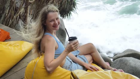 mujer disfrutando de café junto al océano