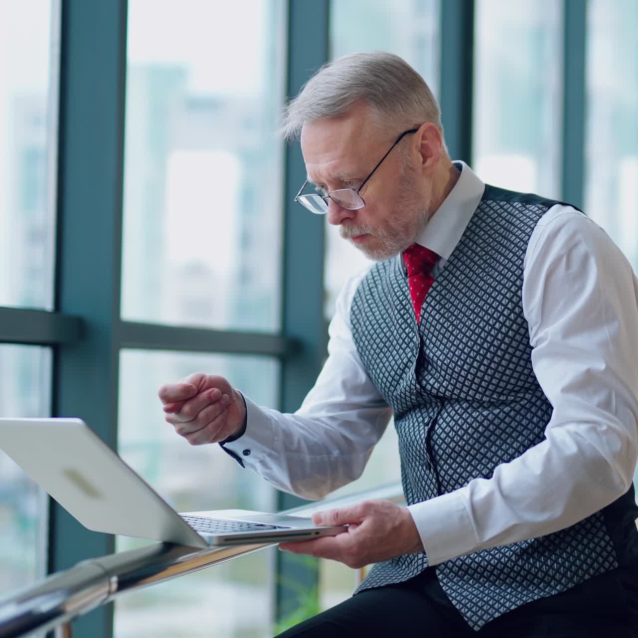 Thoughtful businessman working on computer in front of the window with city view. Video of working process in big company.