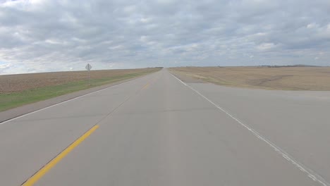 pov driving on a paved rural road between harvested fields in rural south central nebraska on a cloudy winter day