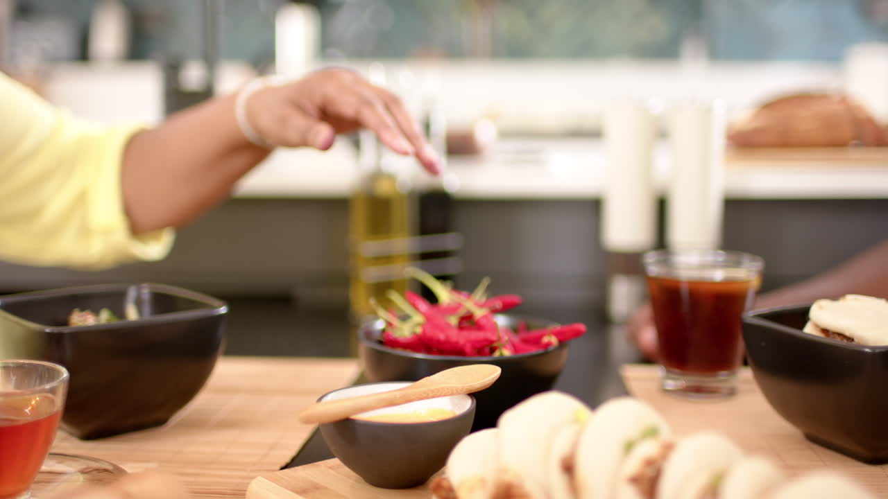 Reaching for olive oil, friends enjoying meal with tacos and drinks at table