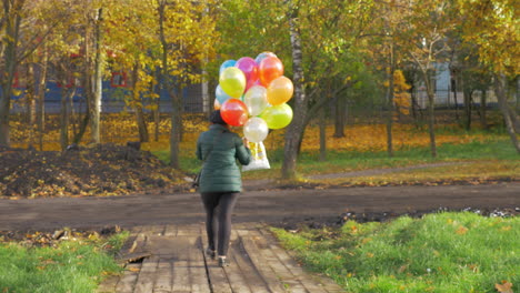 Una-Cámara-Lenta-De-Una-Mujer-Caminando-Con-Globos-En-Un-Hermoso-Día-De-Otoño