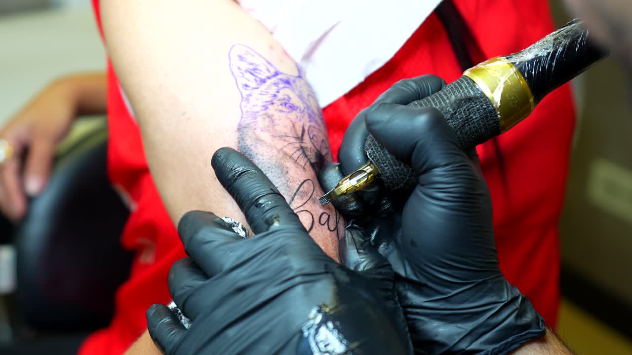 Artist tattooing details of a dog face and applies foam to clean remaining ink