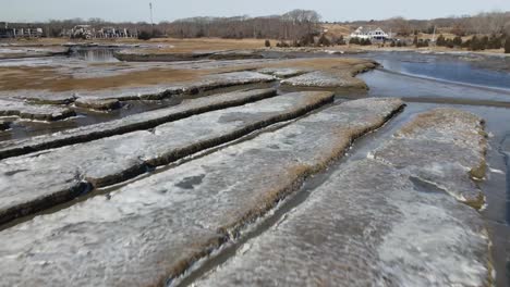 Slow,-sliding-drone-forward-over-the-scarred-and-frozen-marshes-of-a-coastal-town-in-New-England