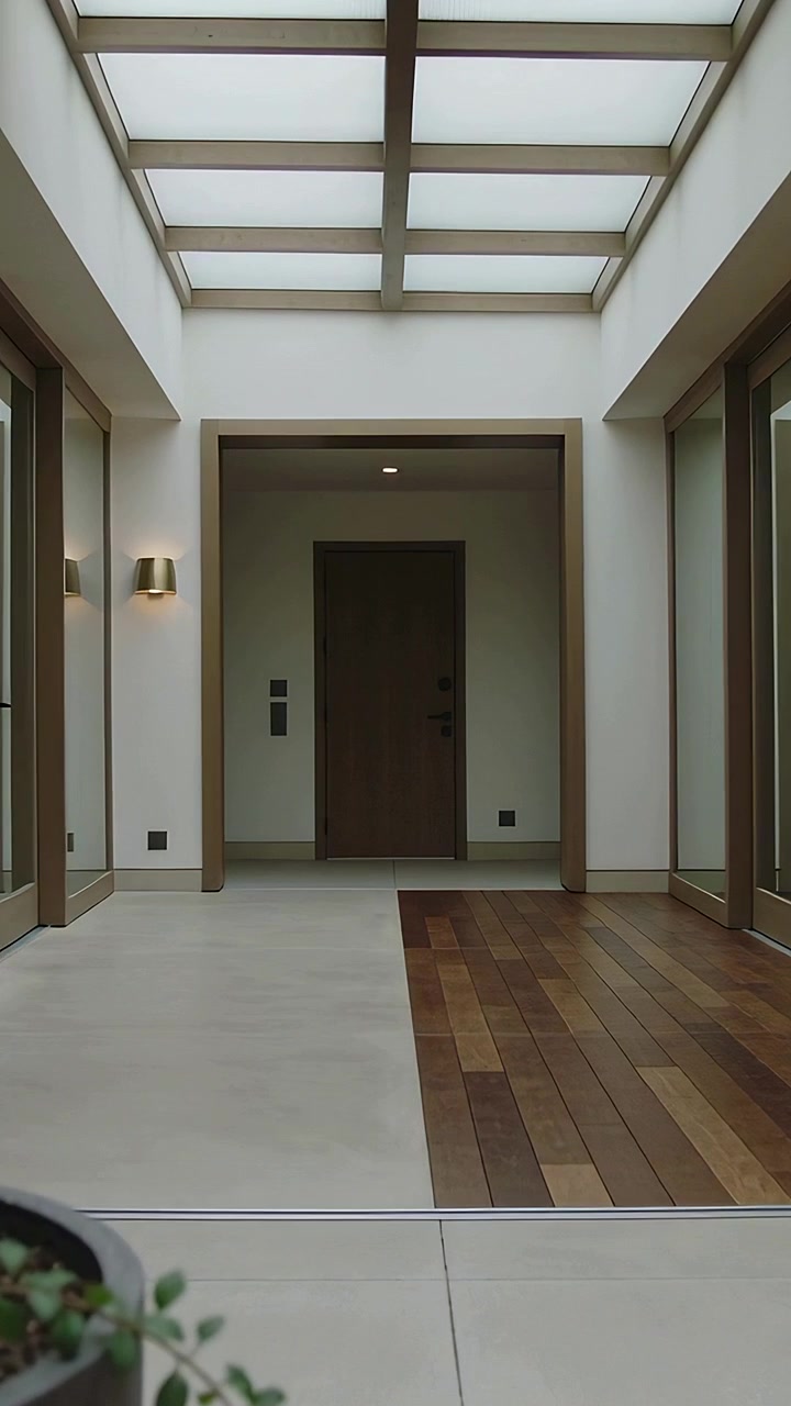 Vertical video: Moving camera from low plant revealing wood door under skylight, showcasing entry