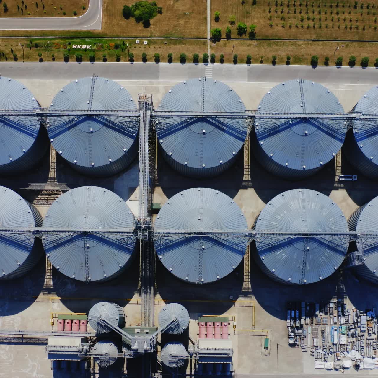 Grain elevators on field. Agriculture grain silos storage tanks. Metal granaries for agricultural products. Top view.