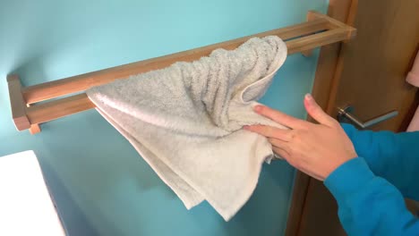 woman wipes her wet hands into white fresh towel hanging on wooden holder