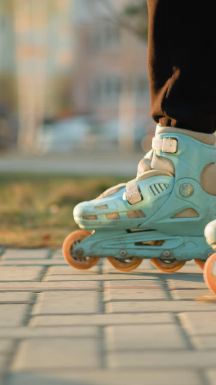 side shot focusing on a person s feet wearing rollerblades as they glide smoothly along a paved path in a park. the motion of the rollerblades, with a green and urban background subtly blurred