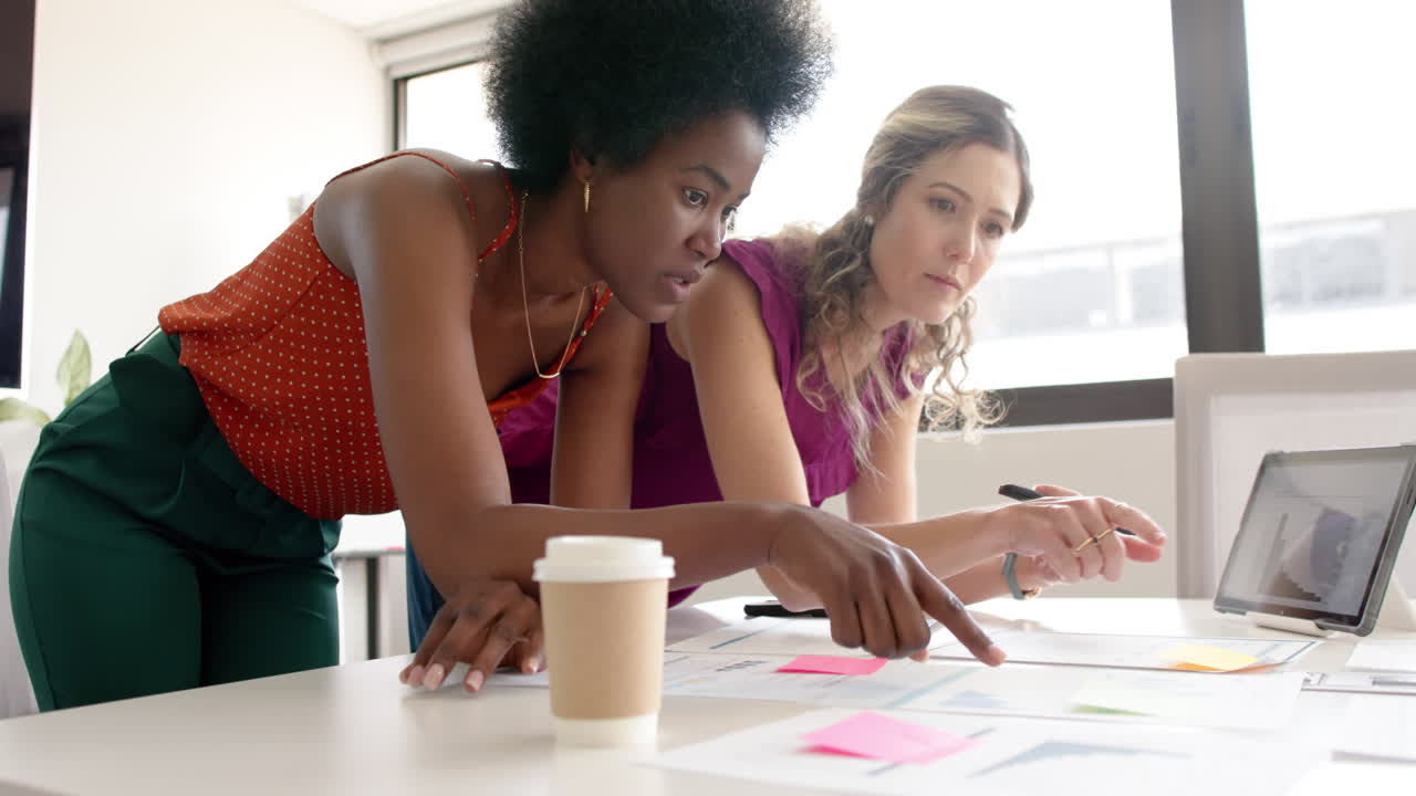 Diverse female creative colleagues brainstorming in meeting in board room, slow motion