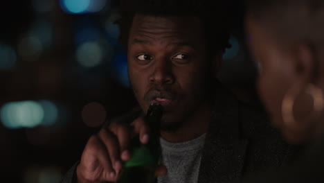 young friends hanging out on rooftop at night chatting having conversation enjoying urban evening african american man flirting with beautiful woman on date