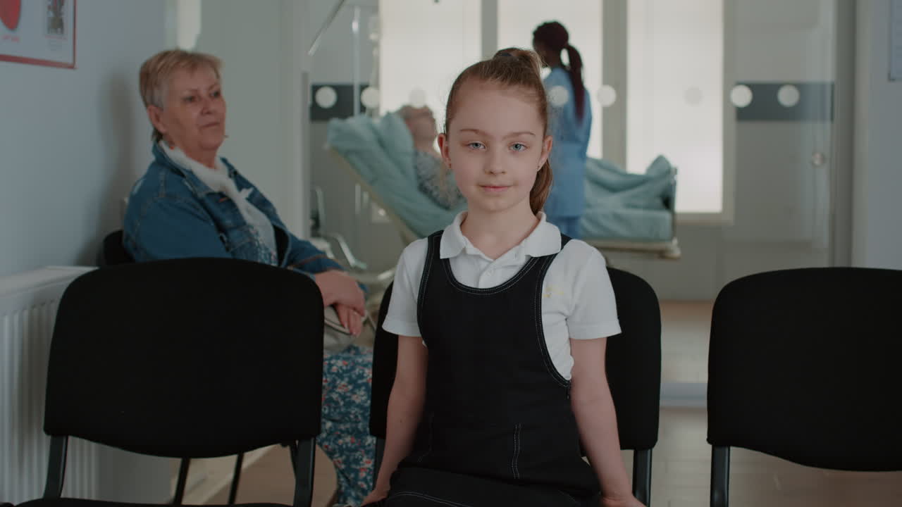 Portrait of child sitting on chair in waiting area at facility