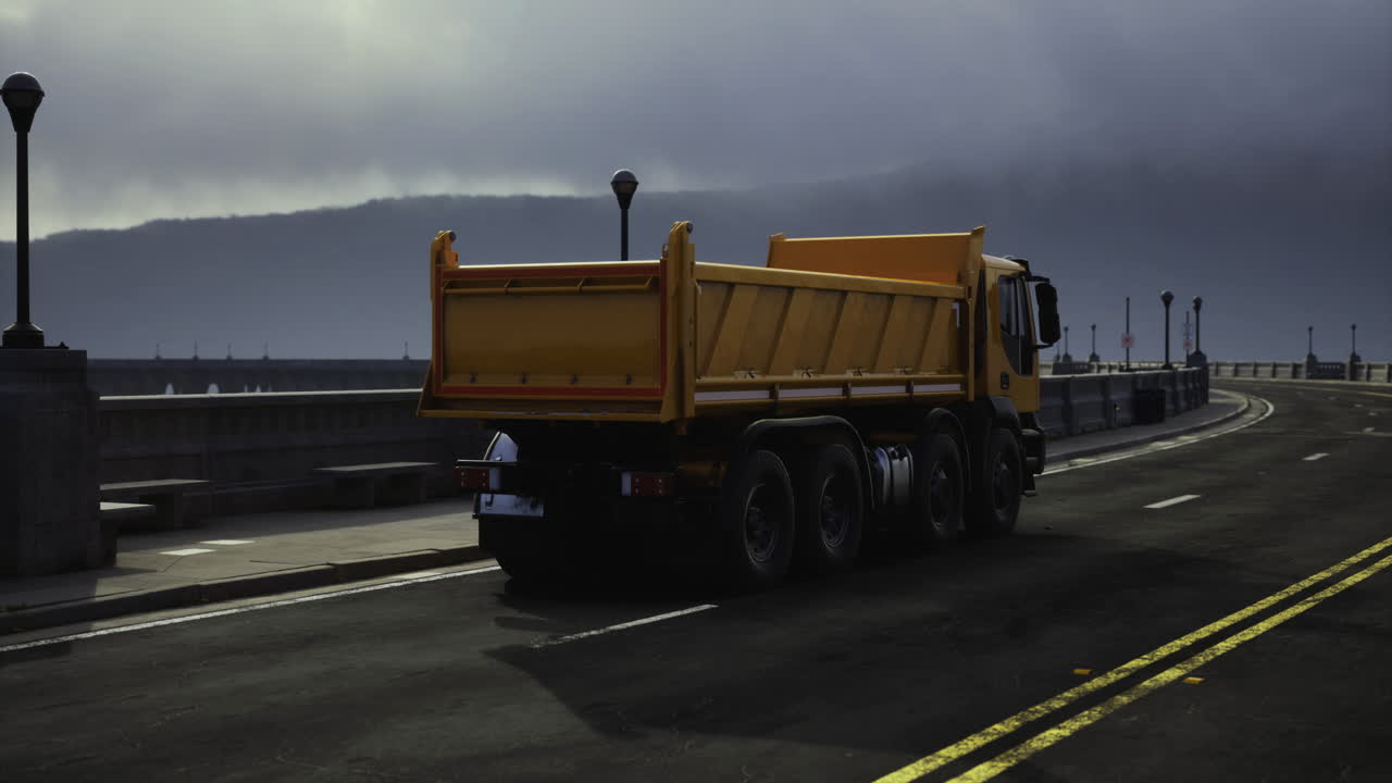 A heavy truck navigates an empty road under a dramatic sky in the evening