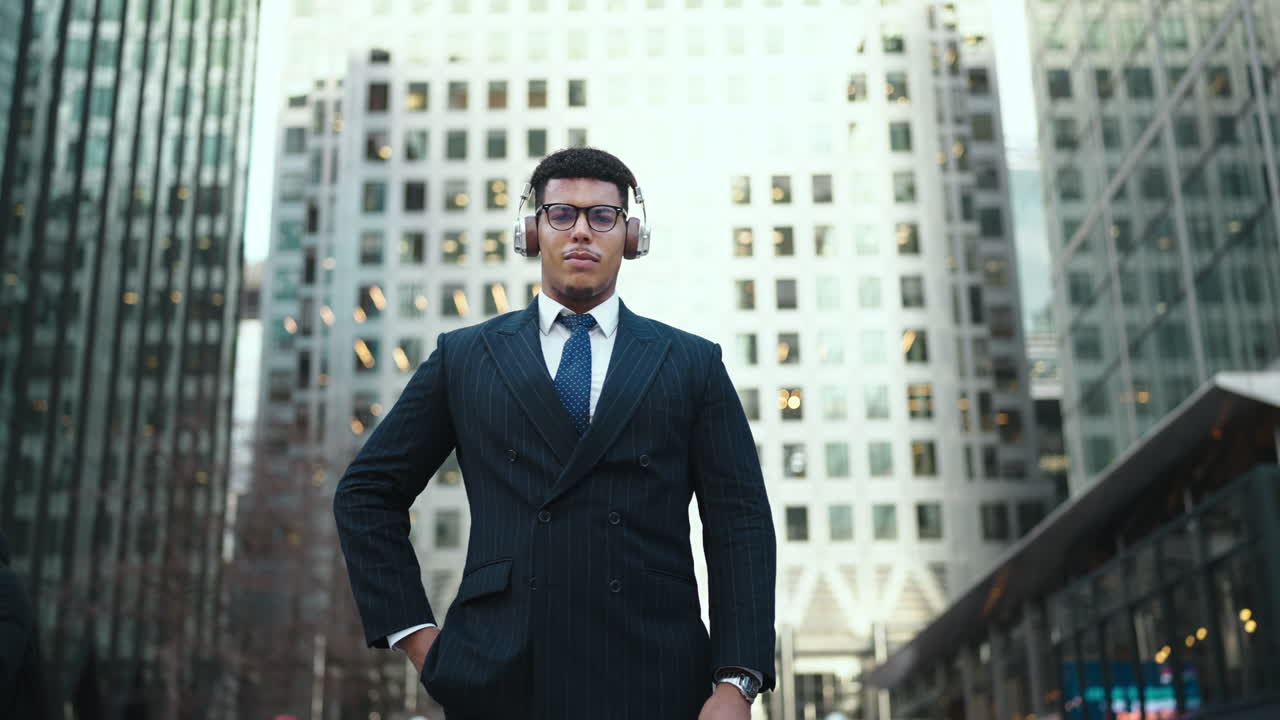 Joven empresario seguro de sí mismo con auriculares sonriendo en una ciudad moderna