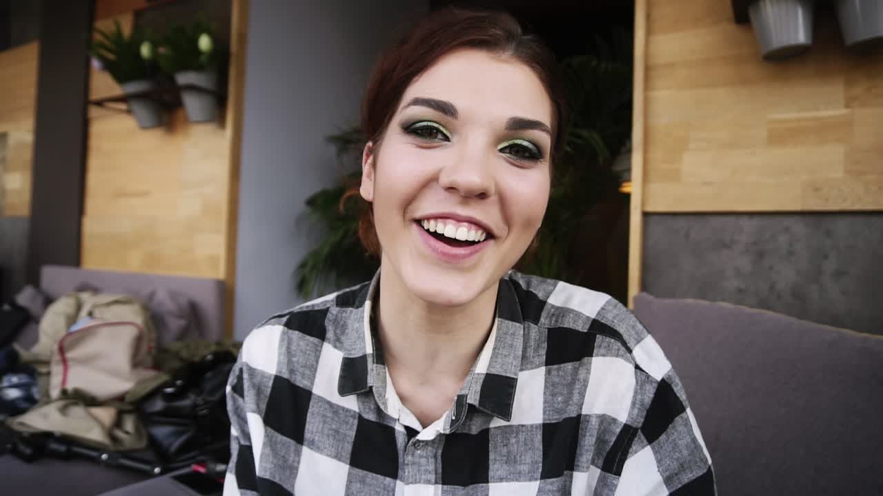 la hermosa morena feliz habla de algo emocionalmente en la cámara, hace gestos con las manos, explica, dice adiós. tarjeta de video. vista frontal. de cerca