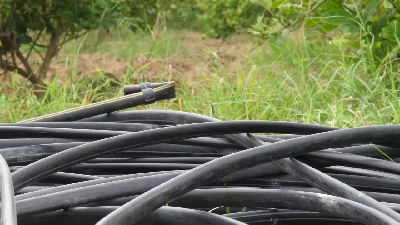 Close Up View Of Coiled Up Black Hosepipes Laying On Ground