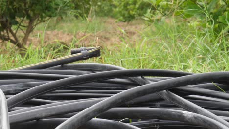 close up view of coiled up black hosepipes laying on ground