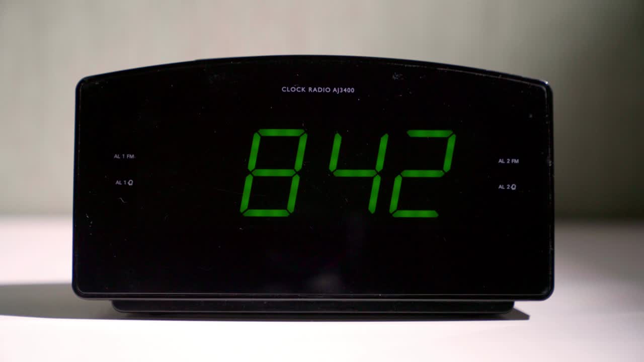 Digital clock shows time with glowing green digits on table