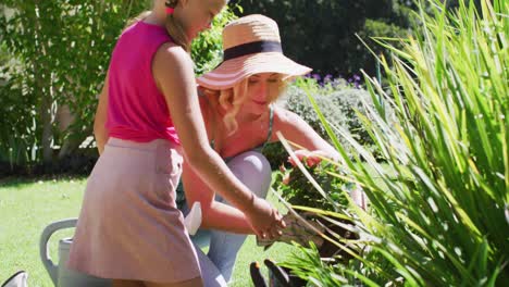 caucasian mother and daughter taking care of plants outdoors