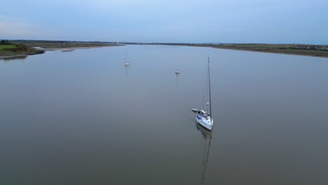 Yachts-on-windless-wide-river-at-dusk-on-the-River-Wyre-Estuary-Fleetwood-Lancashire-UK