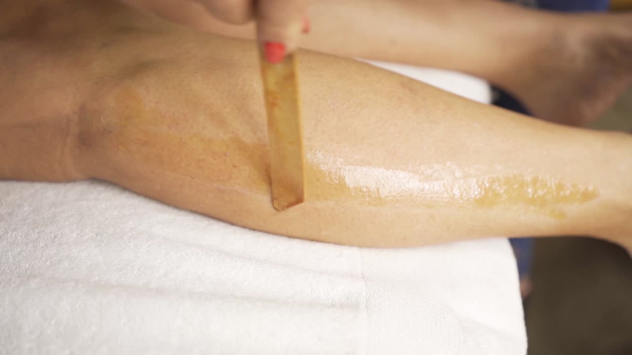 Depilation procedure with wax on the legs slow motion close up