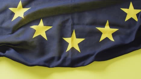 Video-of-creased-flag-of-european-union-lying-on-yellow-background