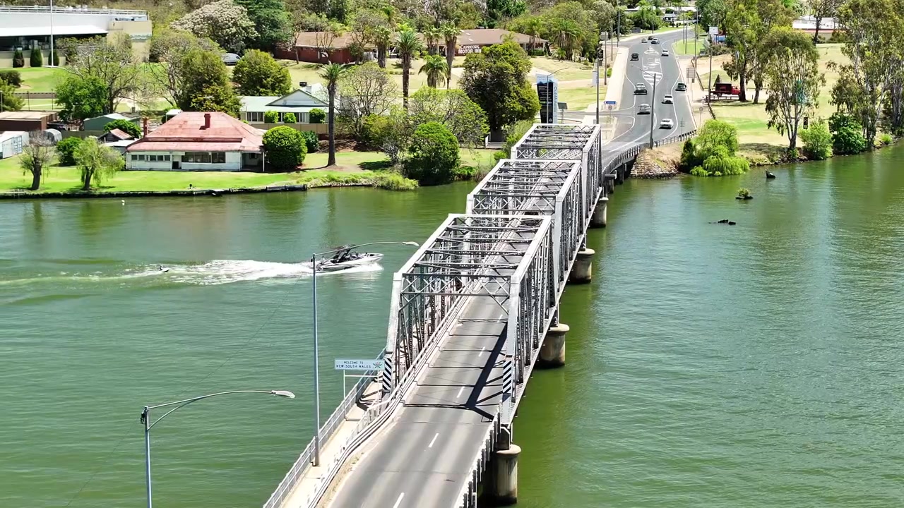 Una lancha motora pasa por el puente de celosía de acero que transporta tráfico hacia las casas de Mulwala.