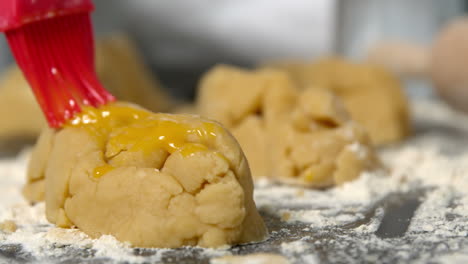 chef brushing egg over raw dough