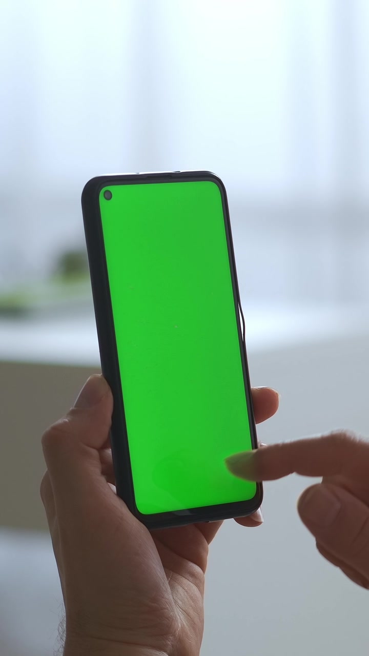 Primo piano di mano con smartphone a schermo verde