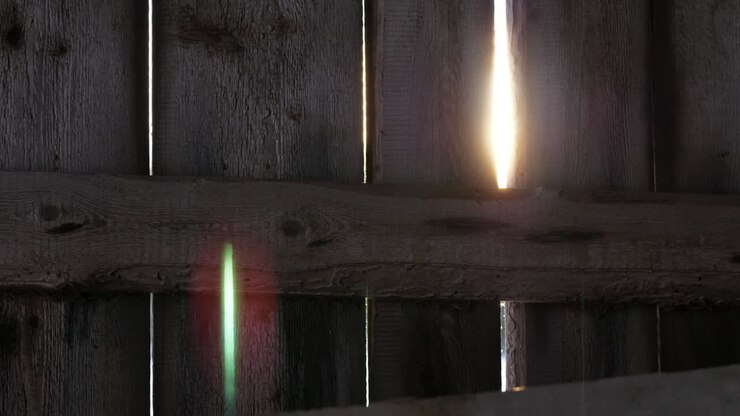 Beautiful sun flares through gaps of wooden fence or wall