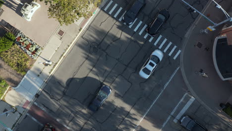 rotating and zoom out shot of cars driving on the road at a t section of road in a city